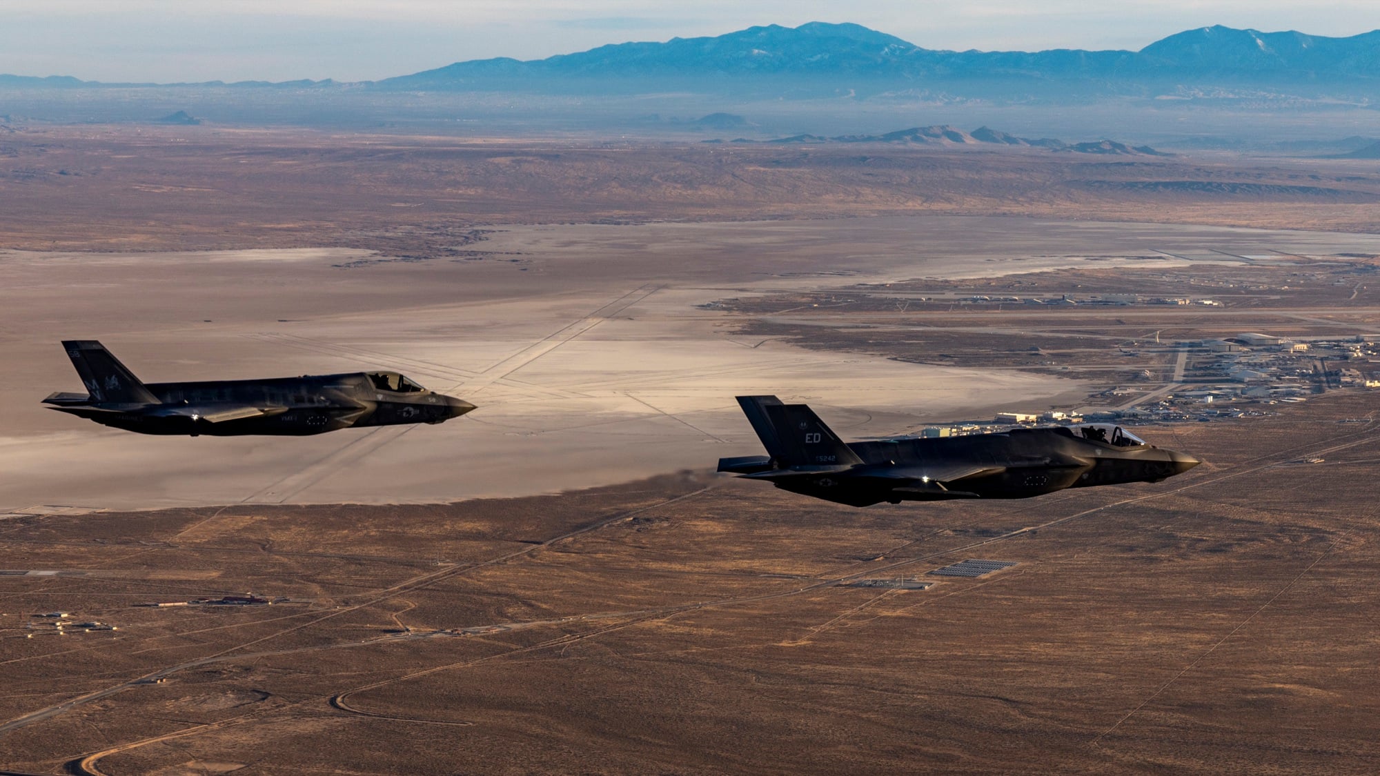 Two F-35 fighter jets in formation over desert terrain