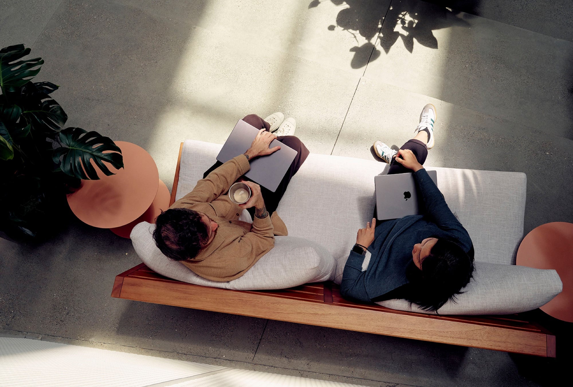Two people working on laptops in soft natural light