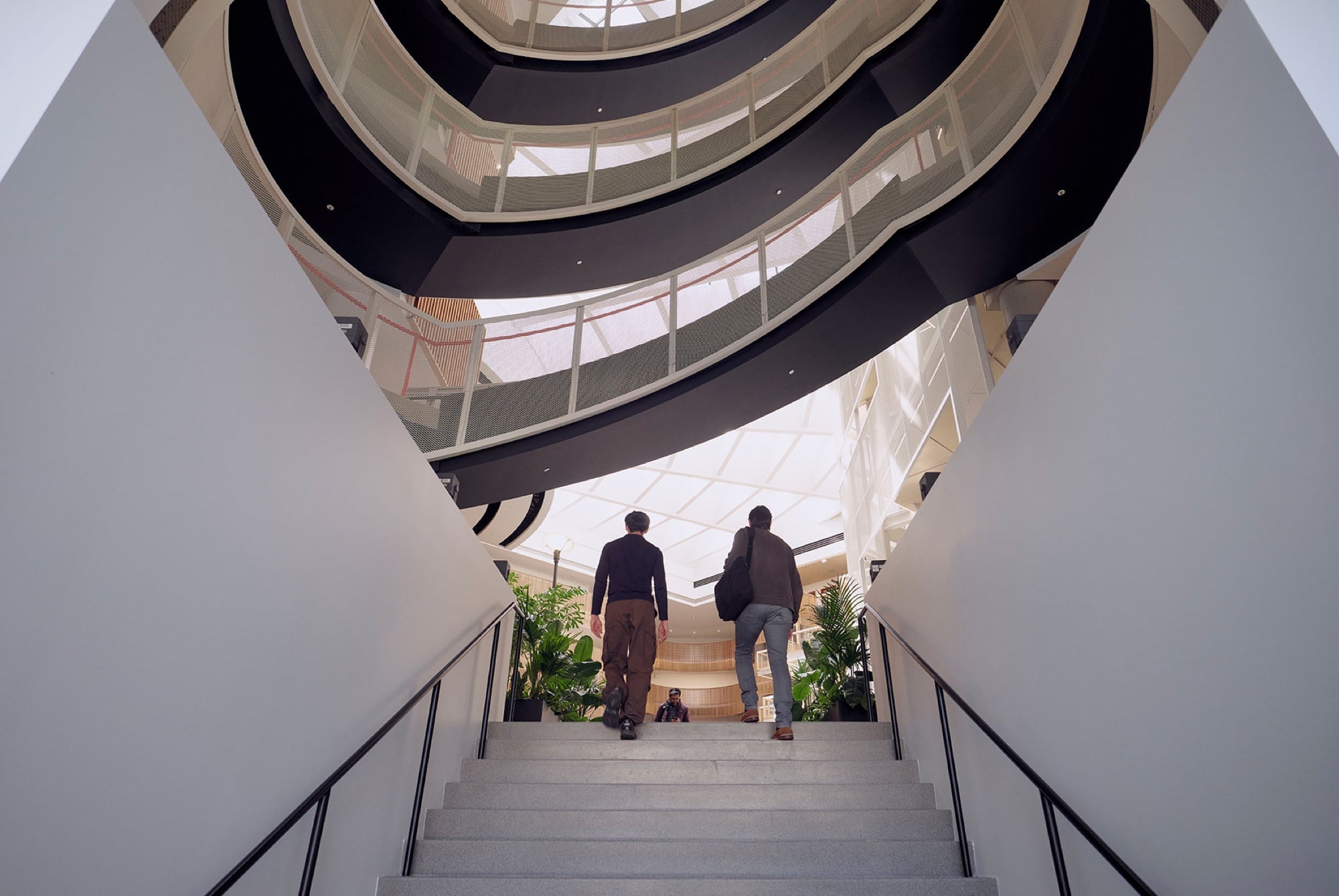 Two people ascending a dramatic modern staircase