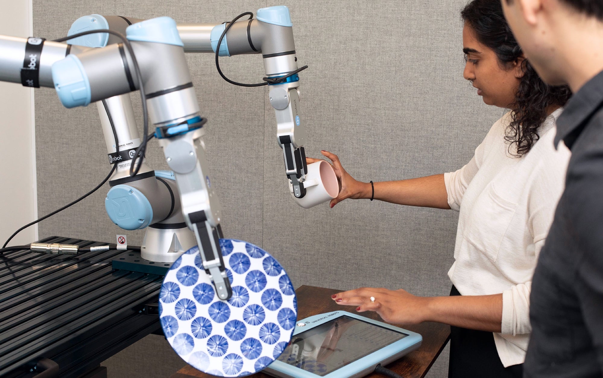 Person interacting with a robotic arm and tablet